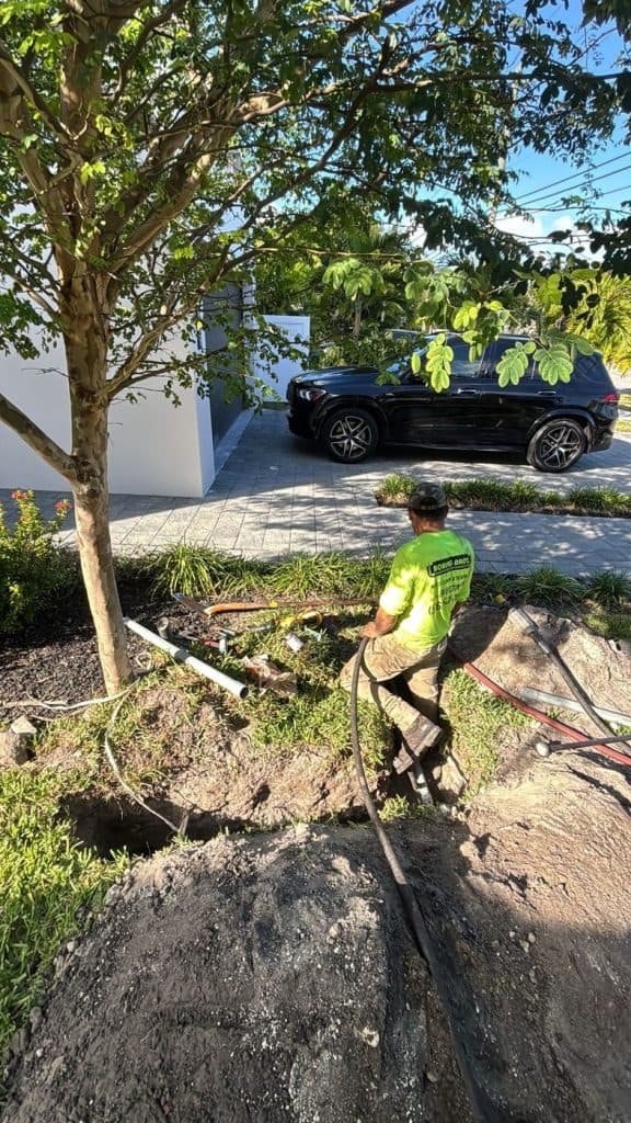 Boring Bros crew member feeding conduit through a directional bore pit at a Fort Lauderdale home