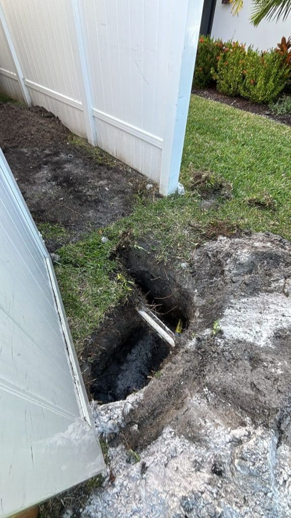 Entry pit for a directional bore beside a property fence — serving Alpharetta, GA