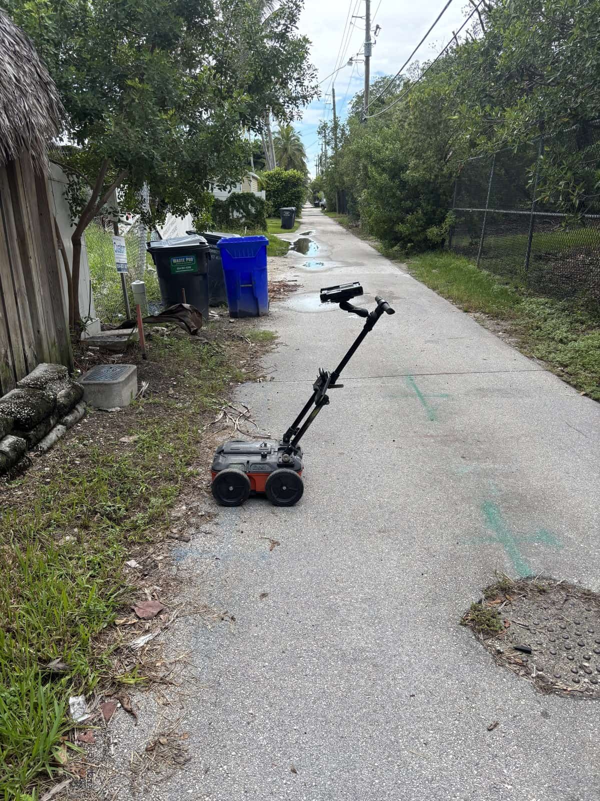 Ground penetrating radar cart in a concrete alley with green locate marks and a patched section of surface in Hollywood