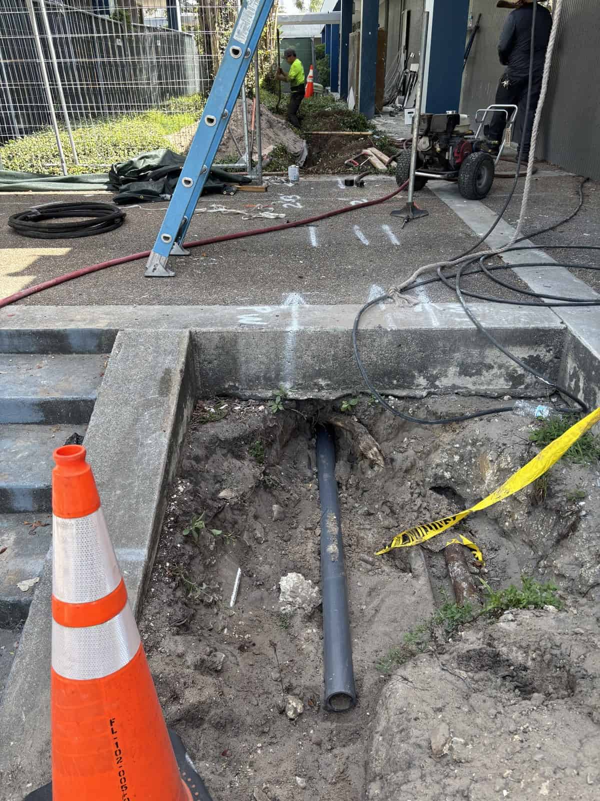 Construction workers installing underground piping at a work site.