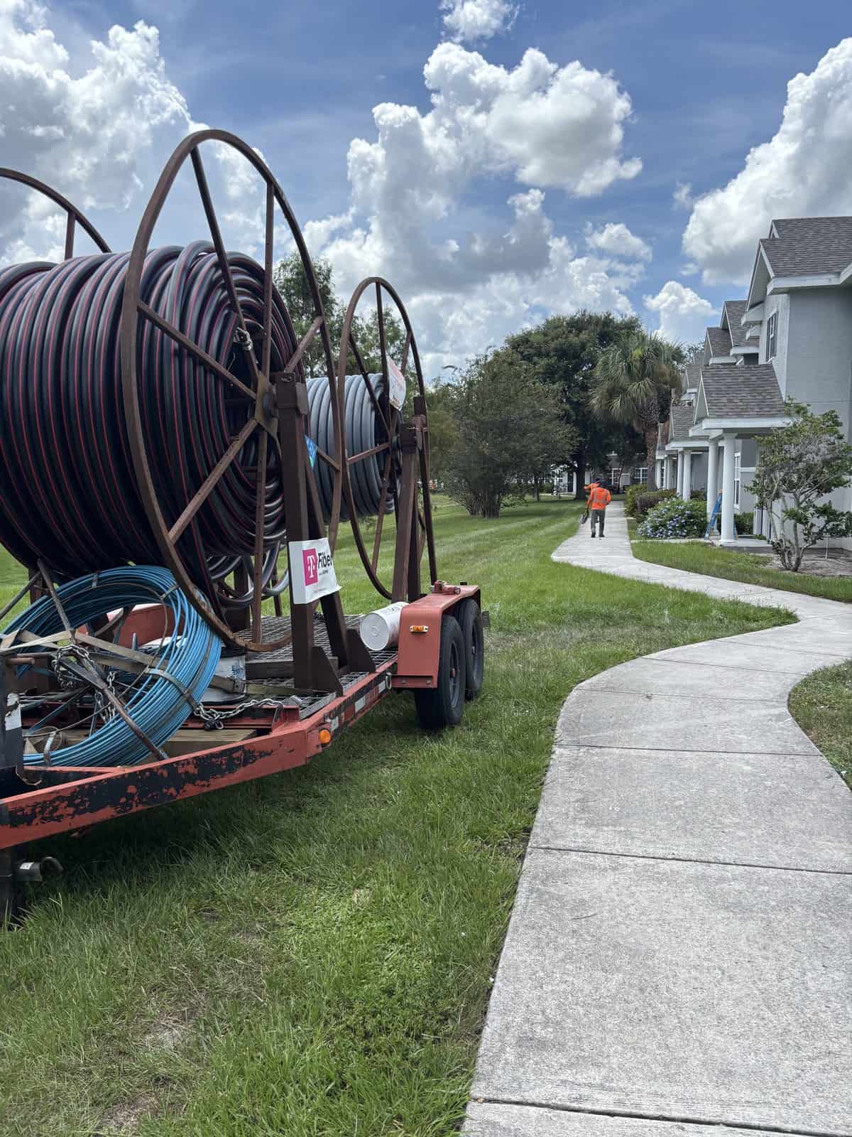 Pipe installation equipment on trailer near residential sidewalk.