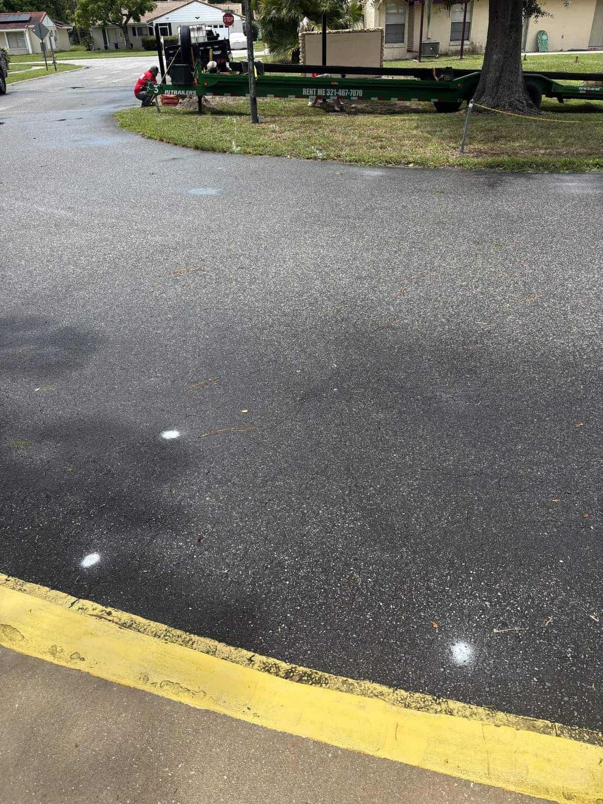 Empty parking lot with yellow curb and white dots on asphalt.