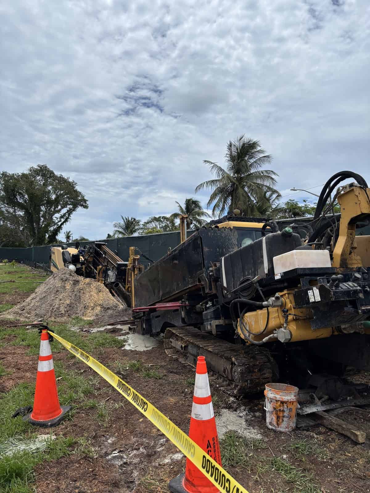 Heavy construction machinery working on a project with safety cones and caution tape.