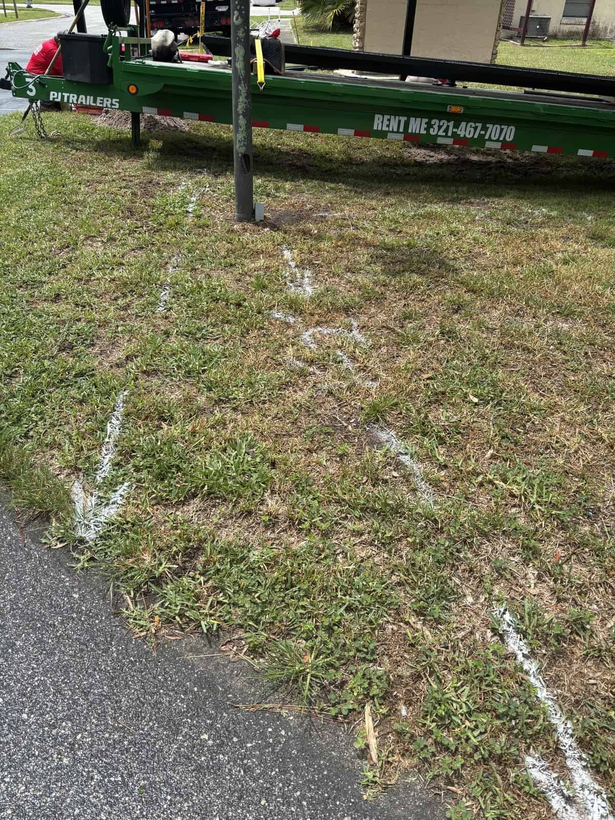 Green utility trailer with Boring Bros branding on grass near parking lot.