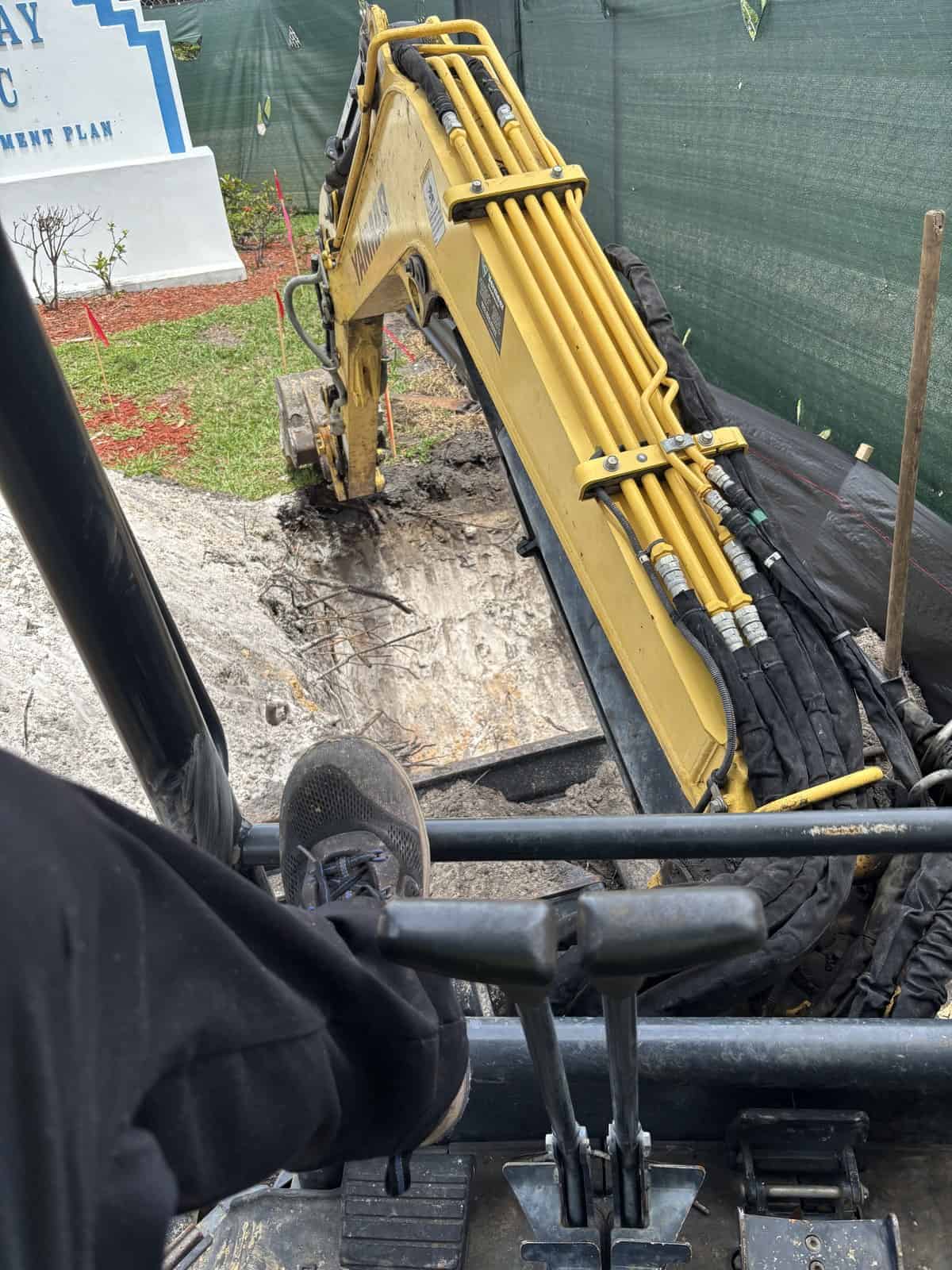 Yellow mini excavator digging in the ground at construction site.