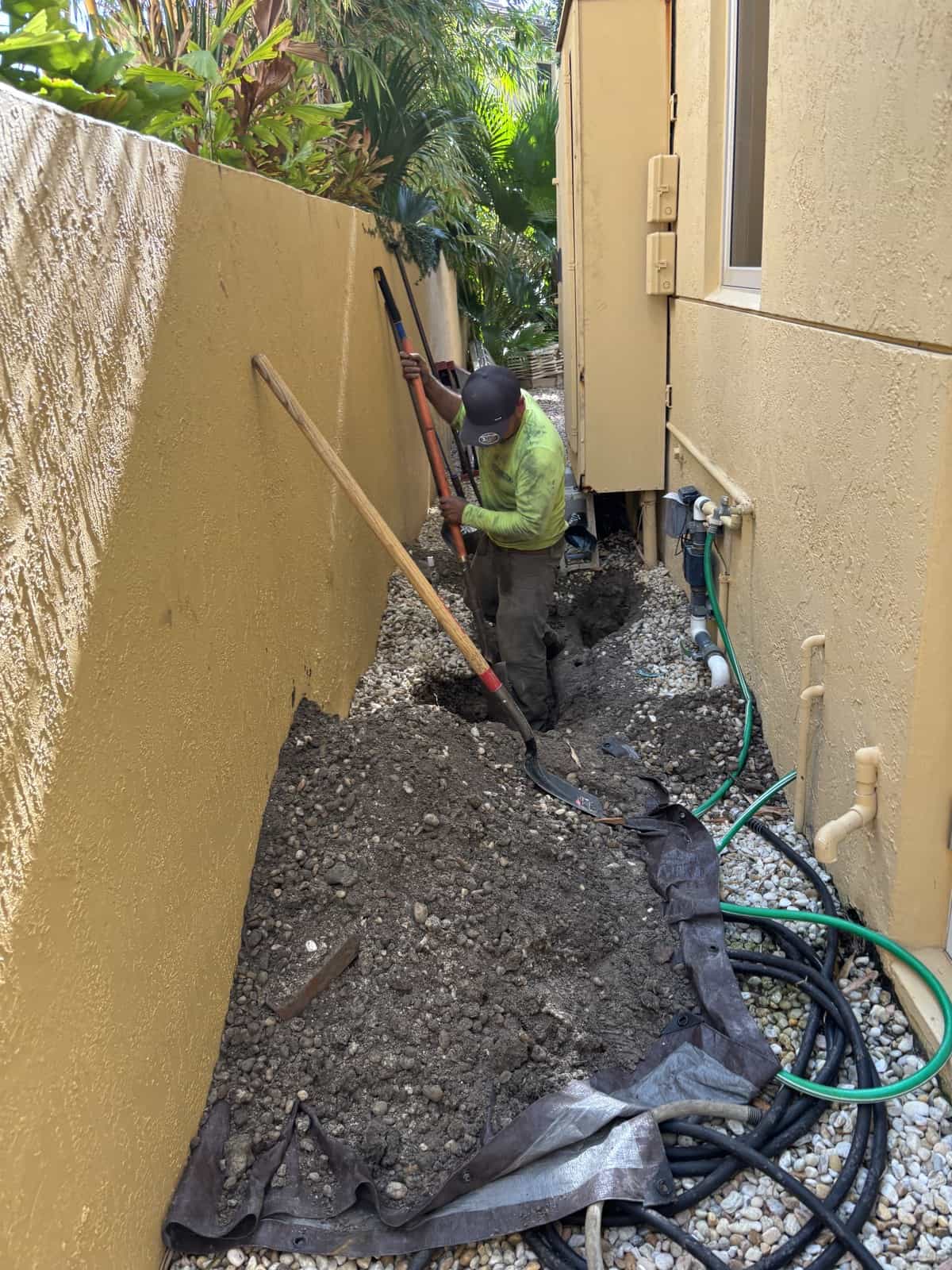 Construction worker installing foundation between house and wall.