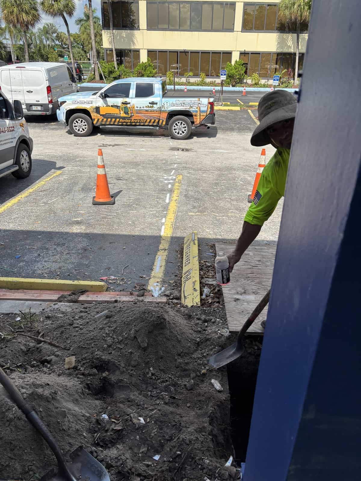 Construction worker digging at Boring Bros construction site with safety gear.