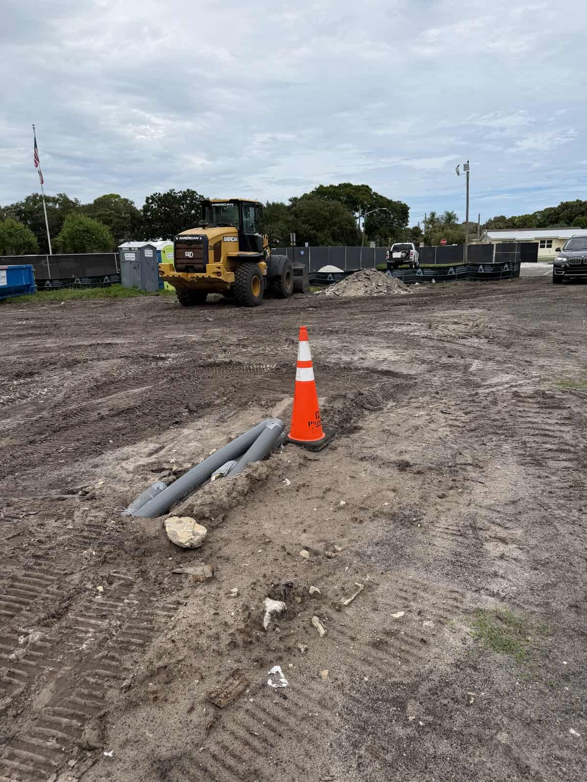 Construction site with bulldozer and pipes on dirt ground.