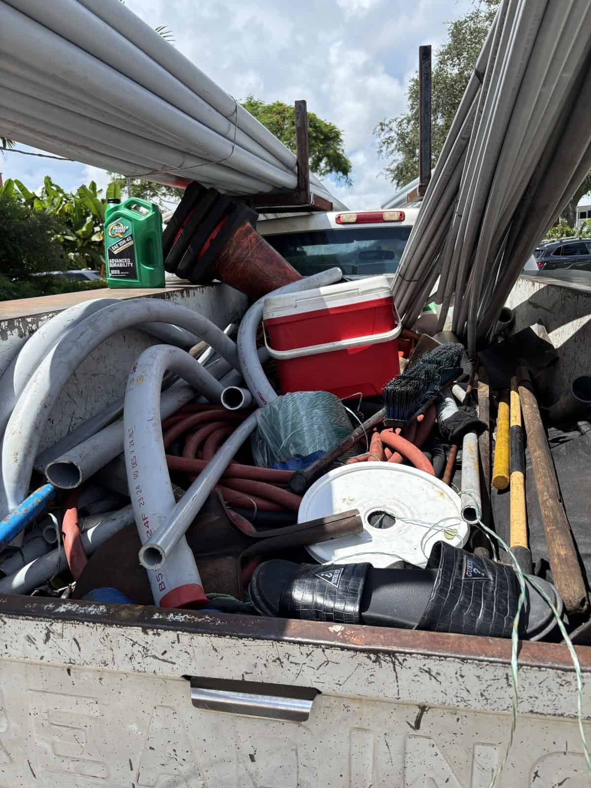 Truck bed loaded with conduit, hose, cable reels and hand tools on a Delray Beach job site
