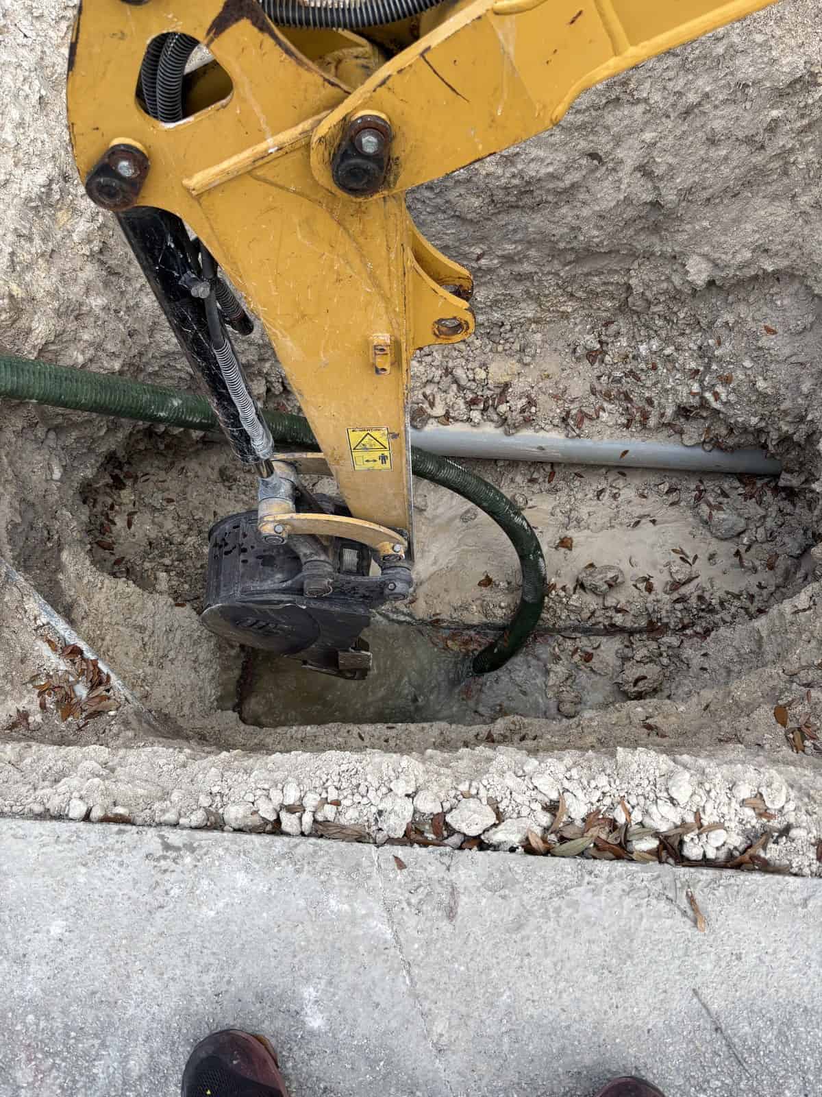 Excavator digging trench at construction site for underground utilities.
