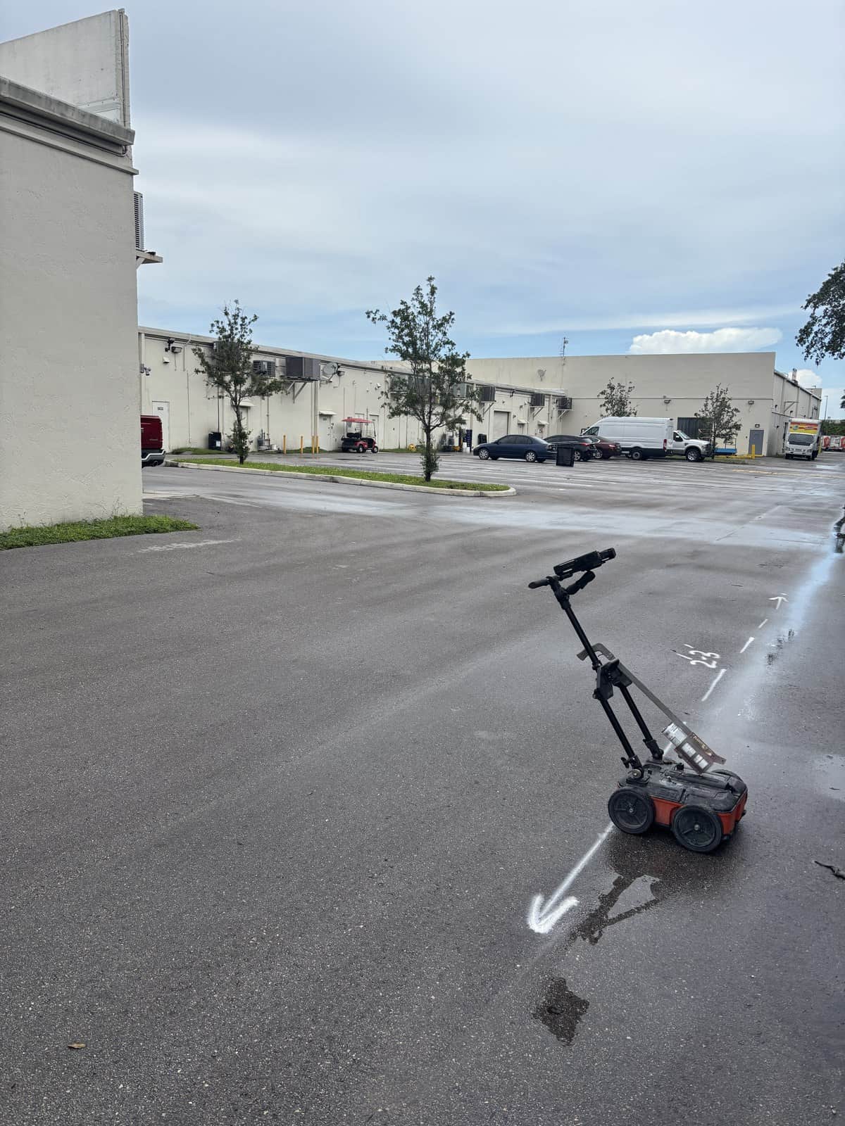 Ground penetrating radar cart standing on wet pavement at a Miami Lakes commercial property with white locate marks