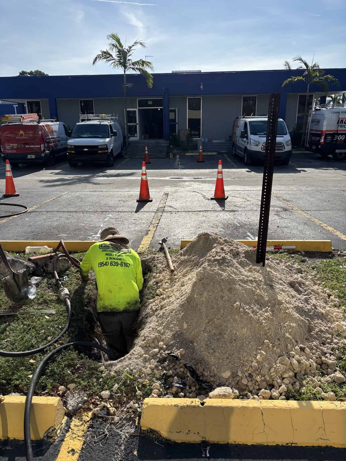 Construction worker repairing underground utilities at commercial site.