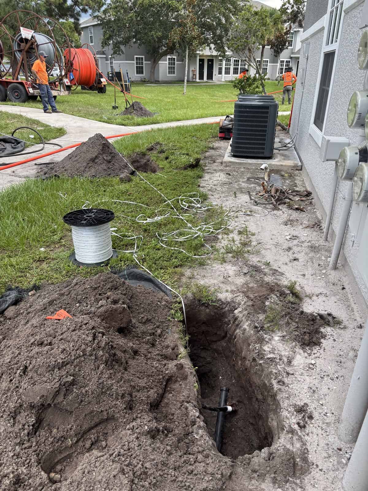 Construction workers installing underground utilities at residential site.