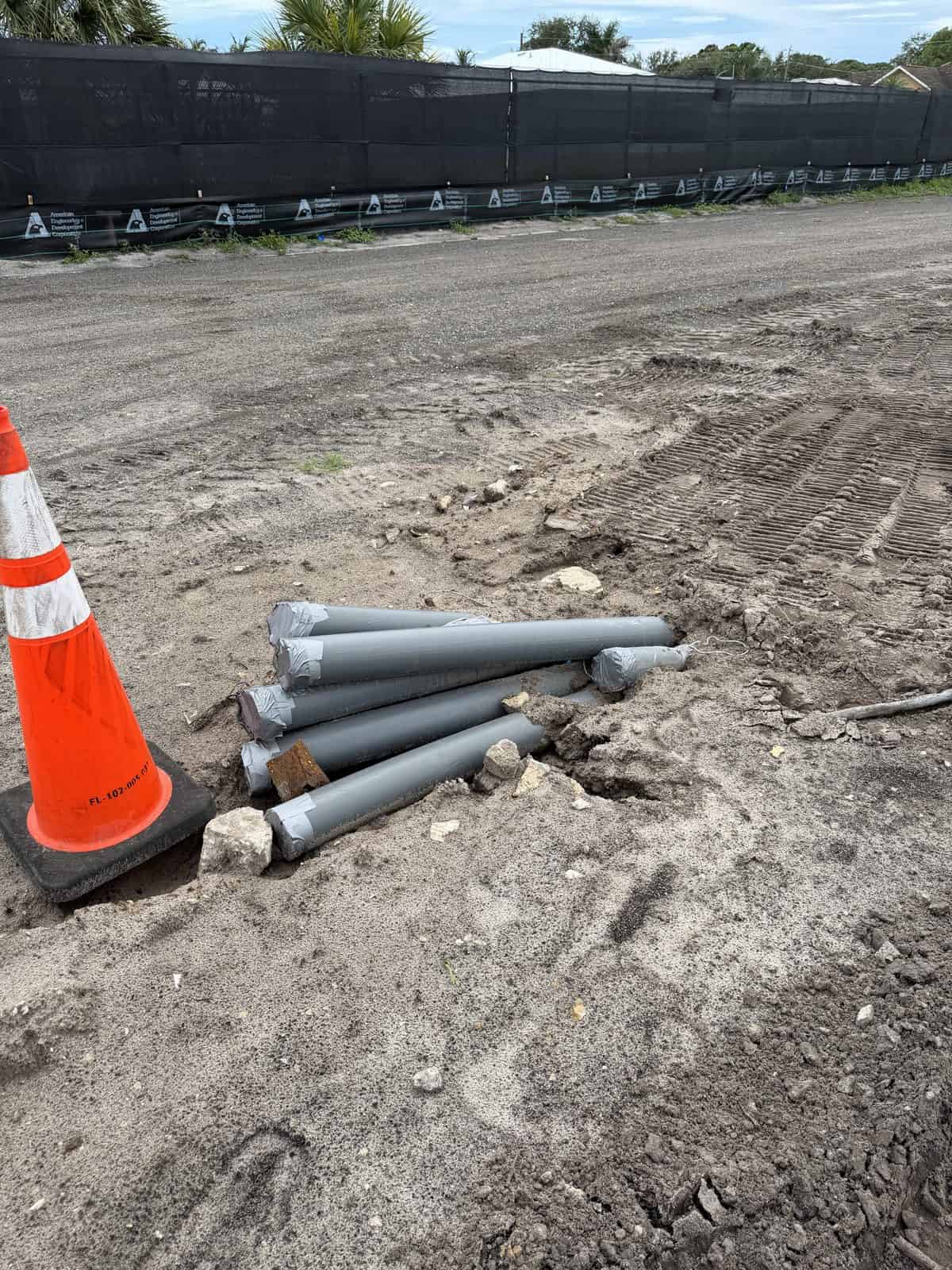 Gray HDPE conduits at the bore exit pit after a directional bore on SE Murray Street, Port Salerno, FL
