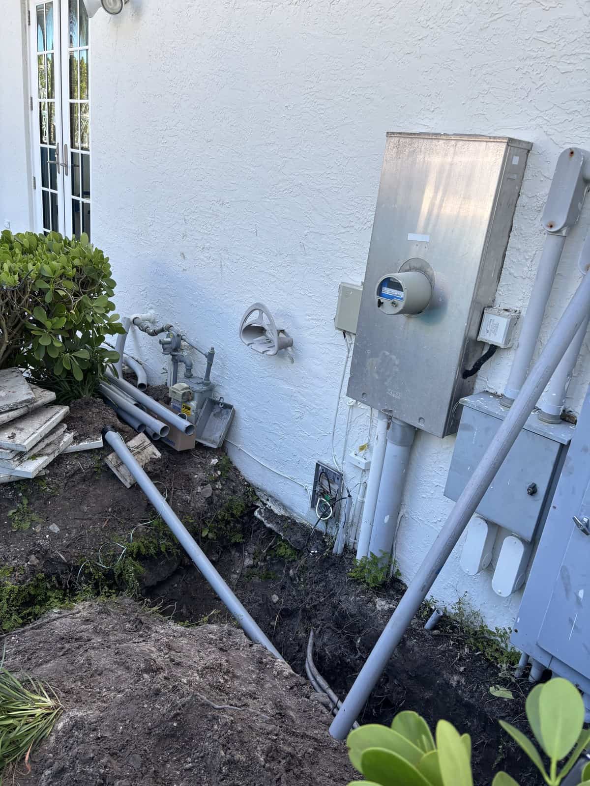 Electrical panel and conduit installation outside a white building.