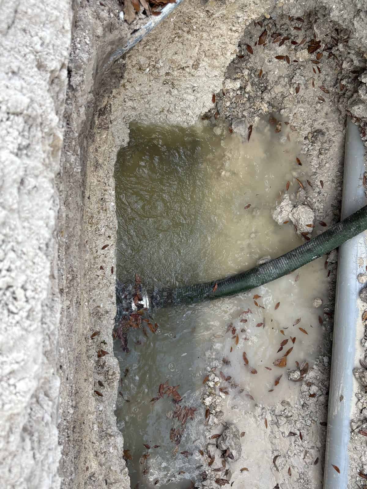 Damaged concrete with water leakage and exposed pipe in construction site.