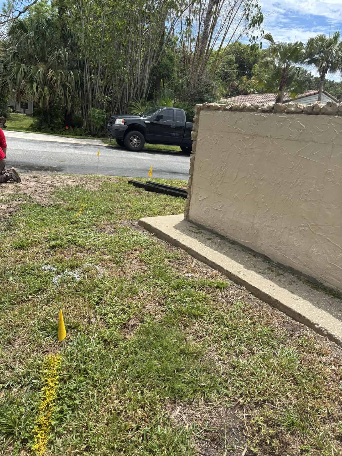 Boring Bros landscaping crew working on yard with yellow markers and a wall.
